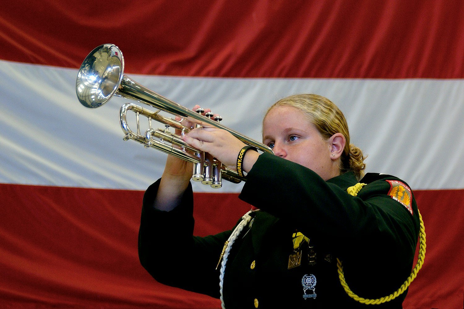 A uniformed bugler playing Taps with an American flag in the background