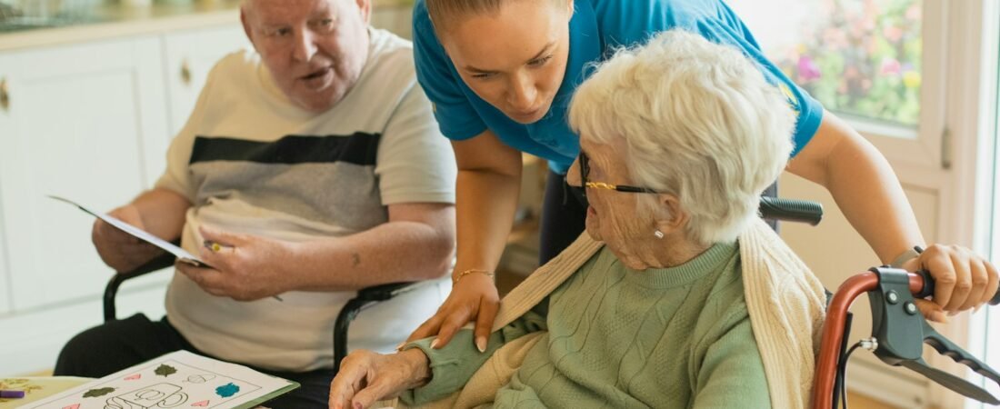 A caregiver assisting an elderly couple with an activity at home