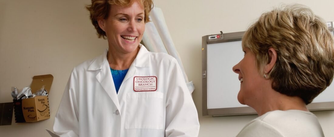 A clinician in scrubs reviewing records on a laptop at a health care facility