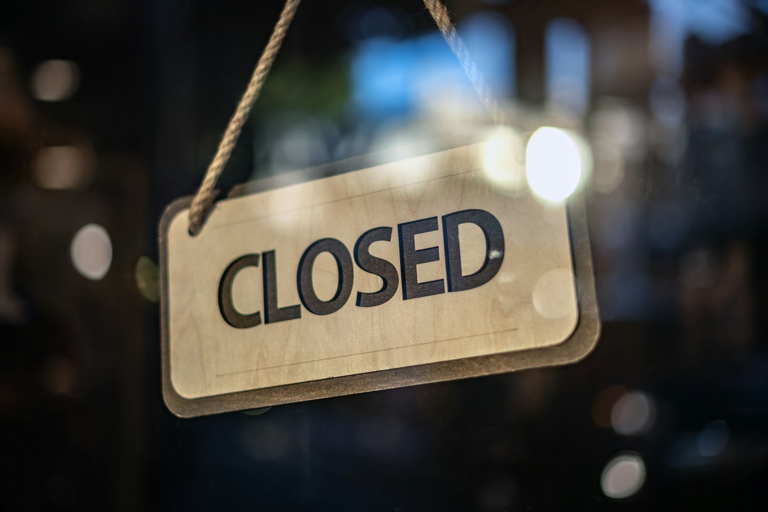 A closed sign hanging from a glass door, representing work that has stopped