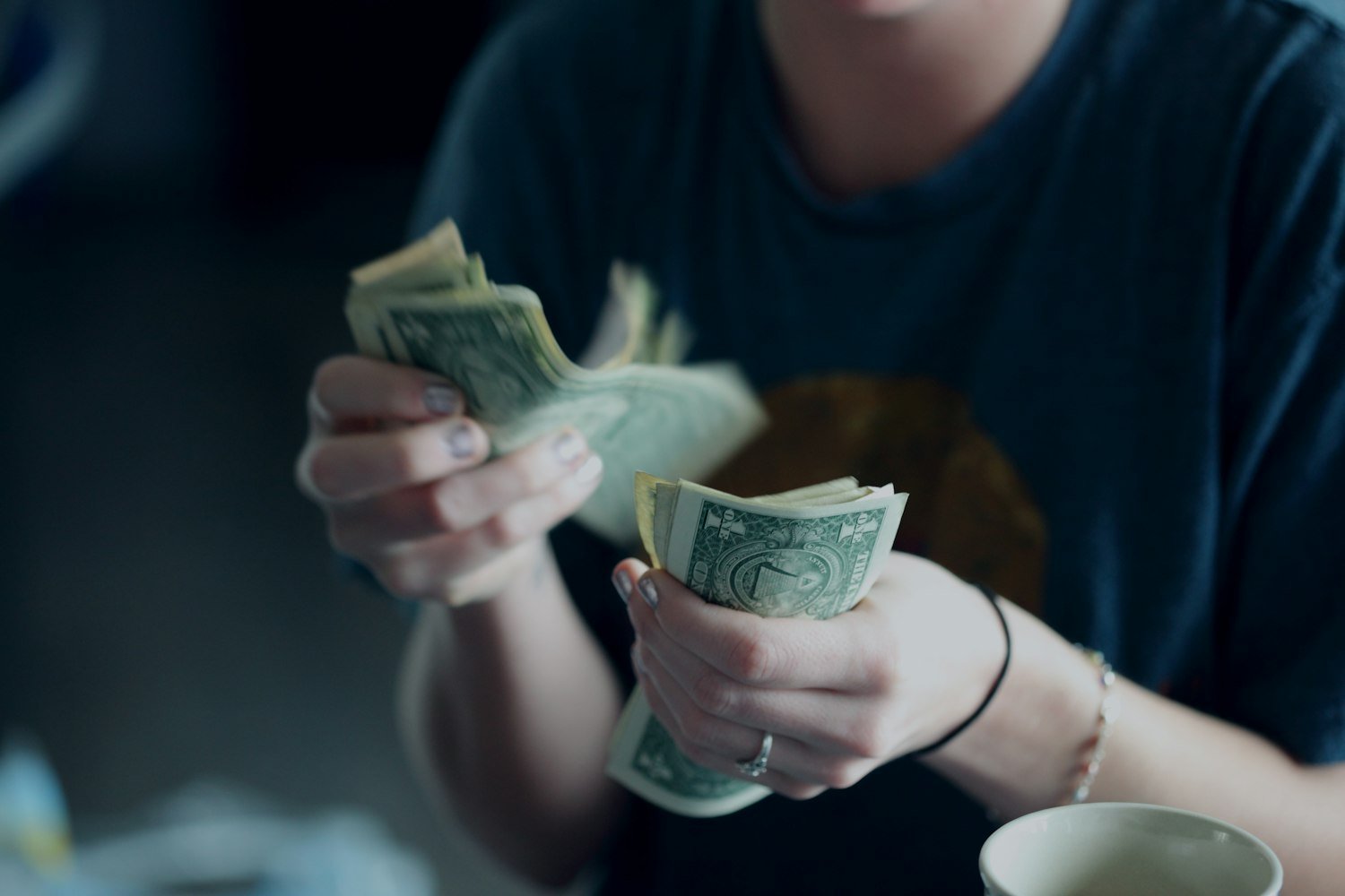 A person counting dollar banknotes, representing the back pay an effective date protects