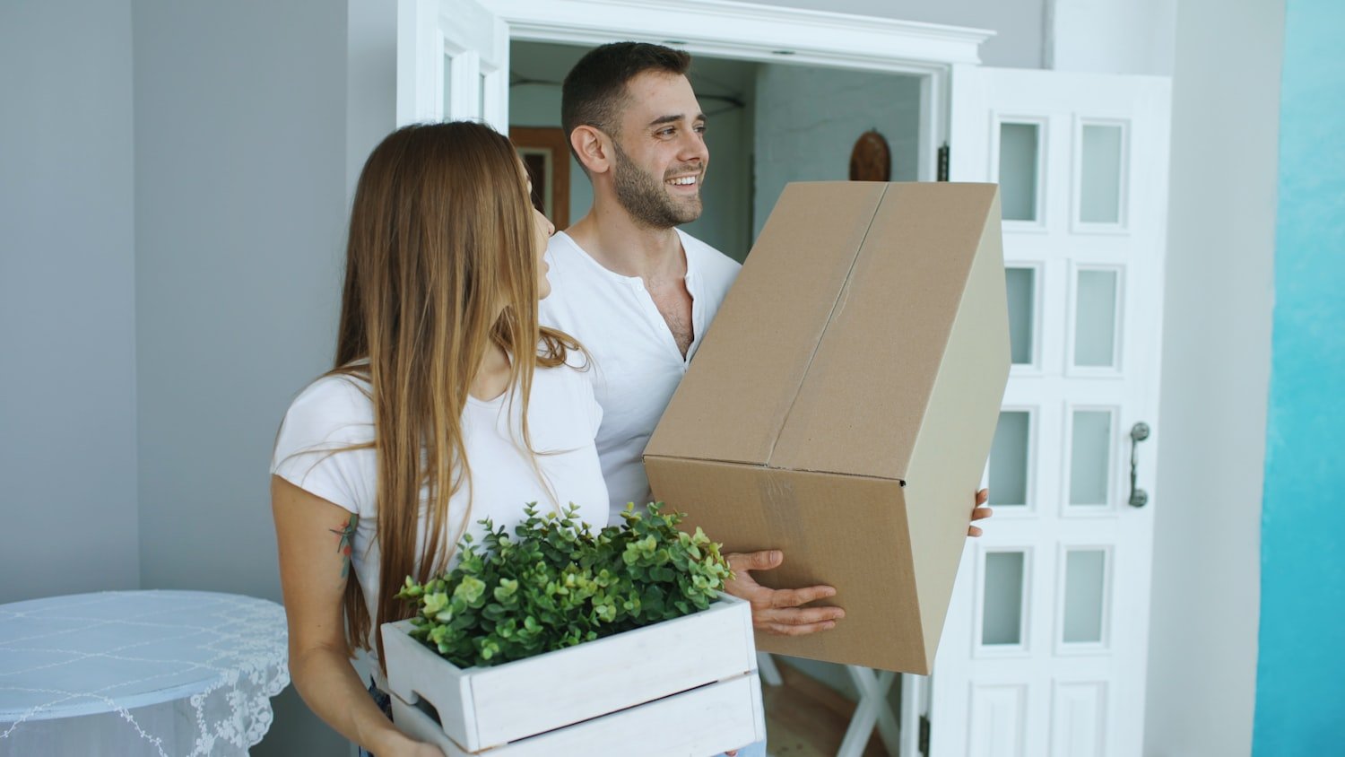 A couple carrying moving boxes into their new home
