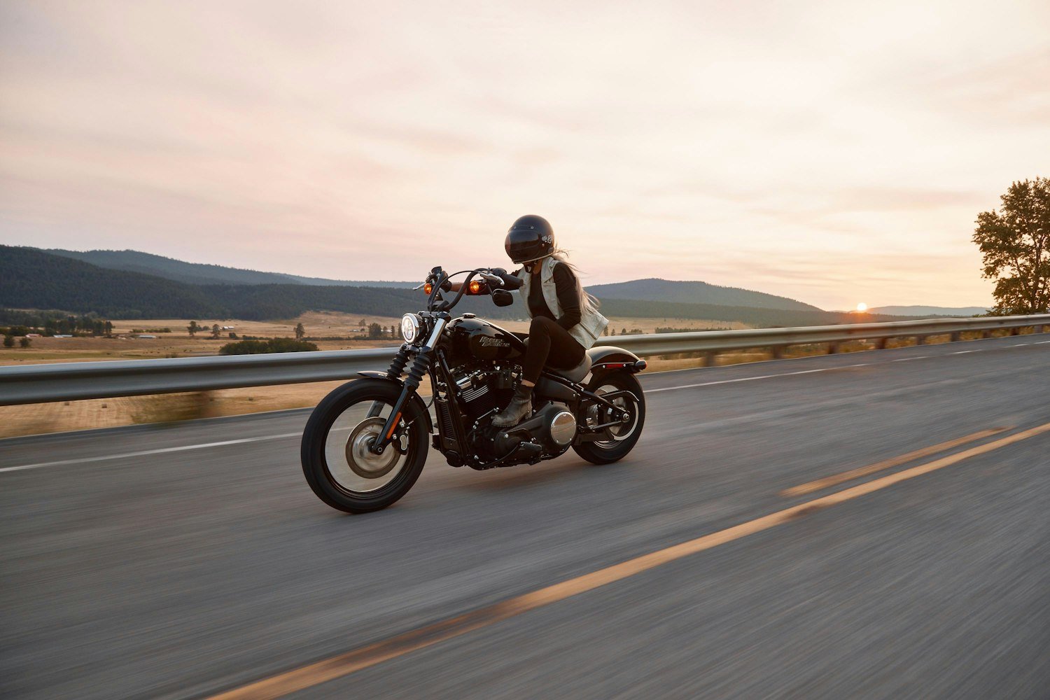 A rider on a cruiser motorcycle traveling along a highway