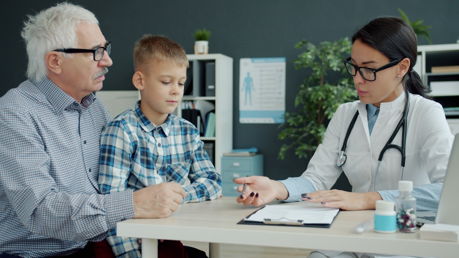 A doctor consulting with a grandfather and grandson in an office