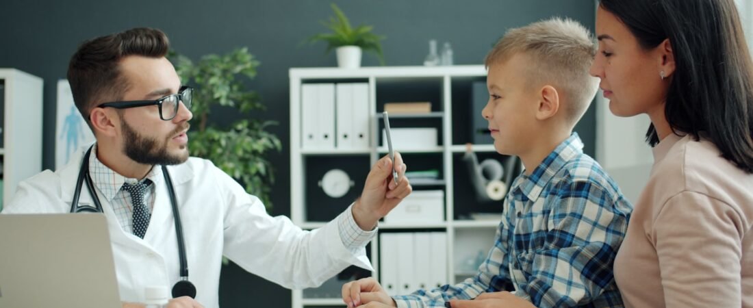 A doctor examining a young child with a parent present, representing family health coverage