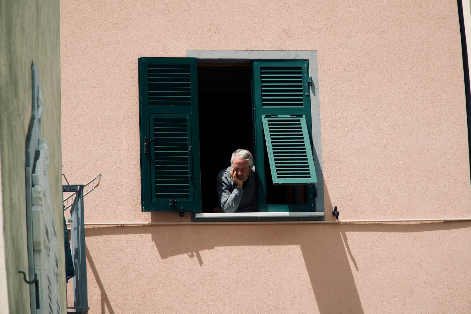 An elderly person looking out an open window, representing a surviving spouse living on the annuity