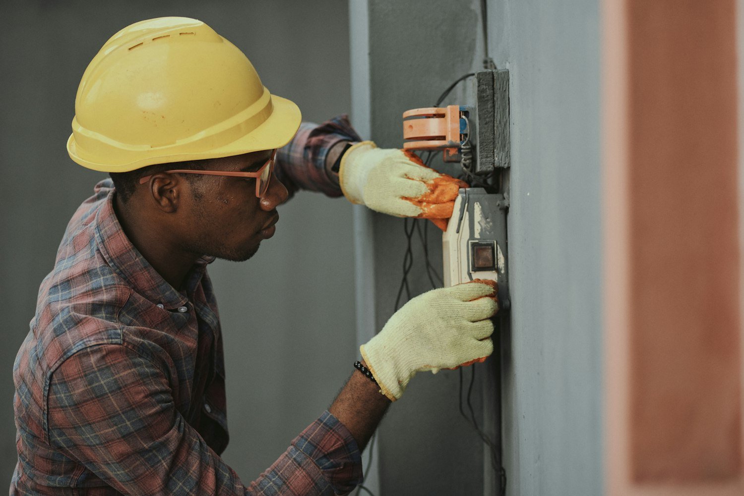 An electrician in a hardhat installing wiring, representing skilled trade training