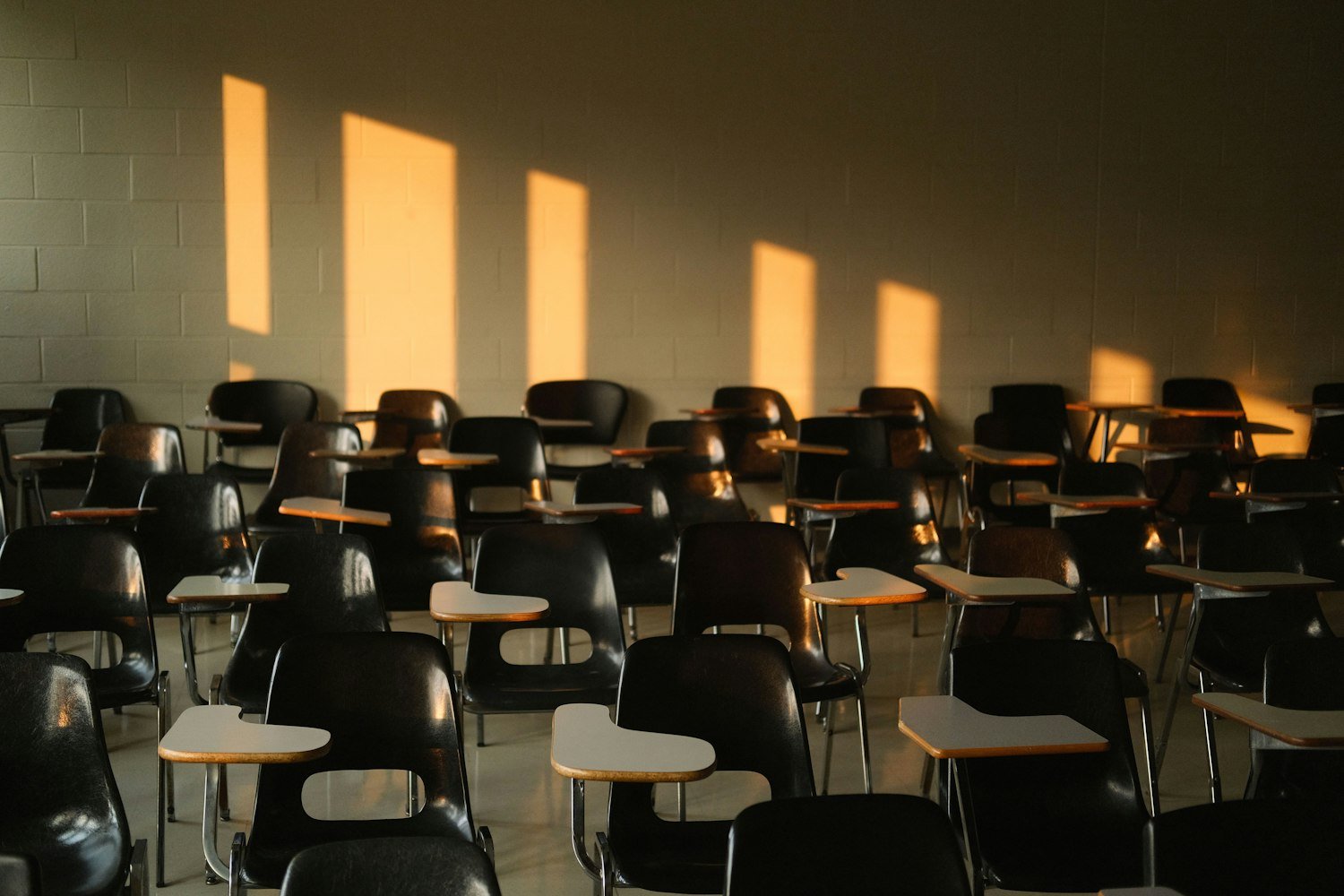 An empty classroom with sunlight casting shadows across the desks