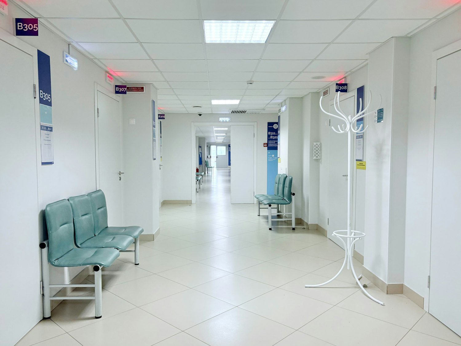 An empty clinic corridor with waiting benches, representing appointment access