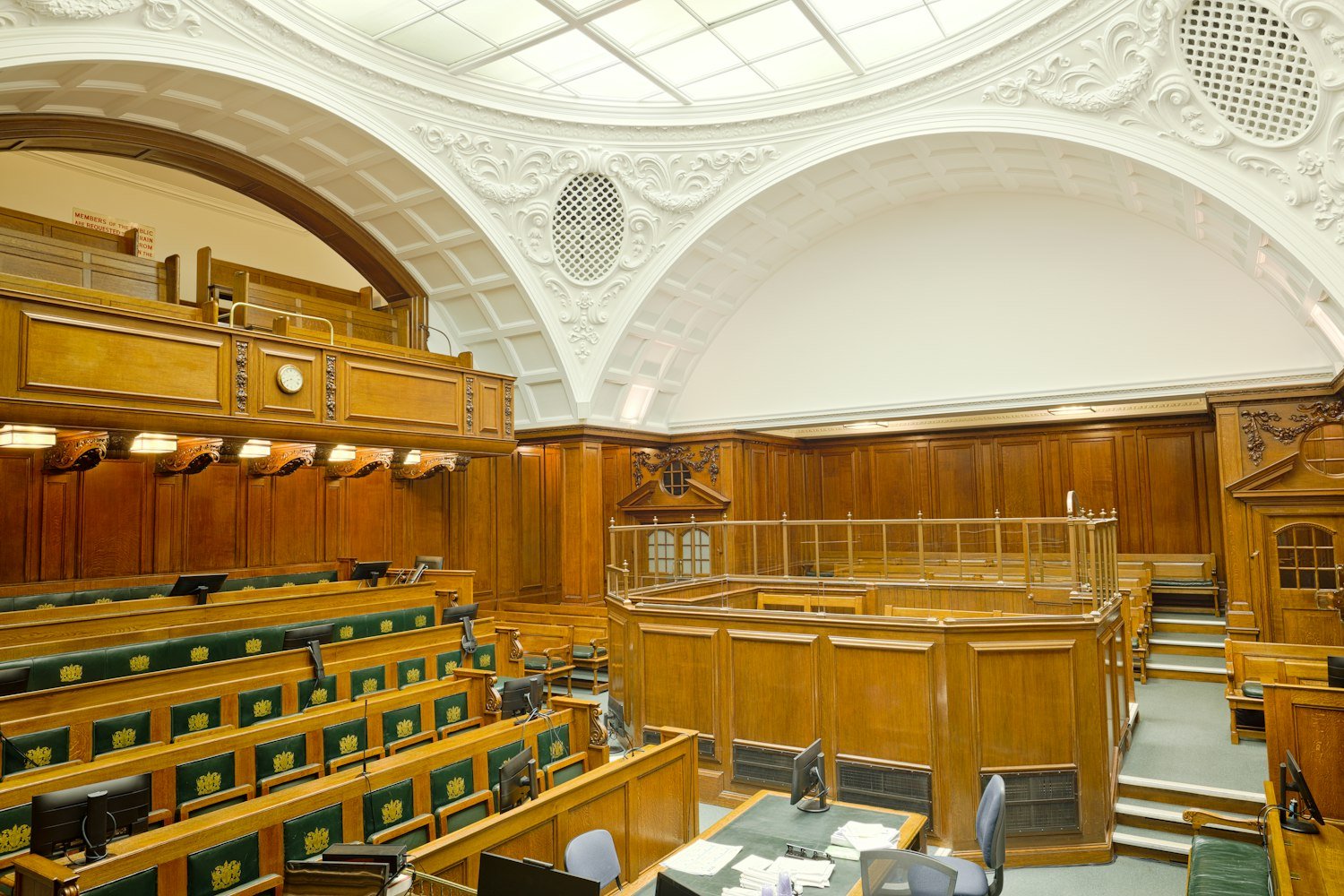 An empty courtroom with wooden paneling and seating