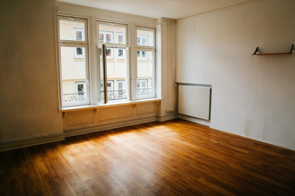 An empty room with a wooden floor and a large window