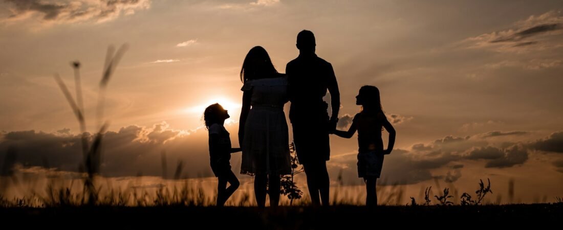 A family standing together in a field at sunset, representing the beneficiaries life insurance protects