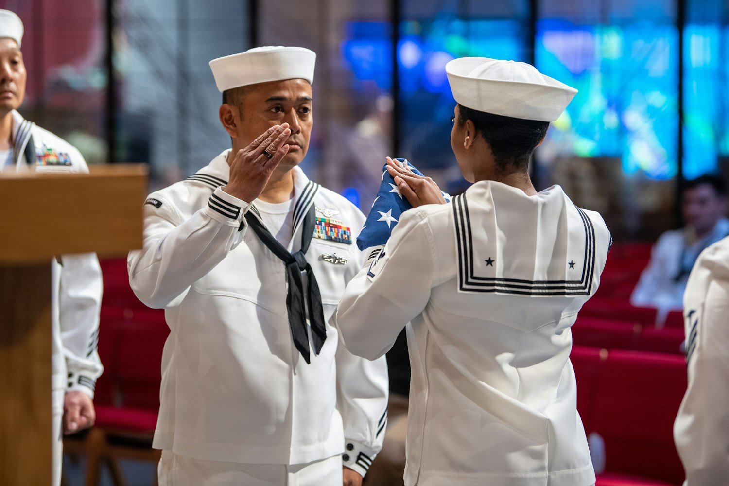 A sailor receiving a folded American flag during an emotional ceremony