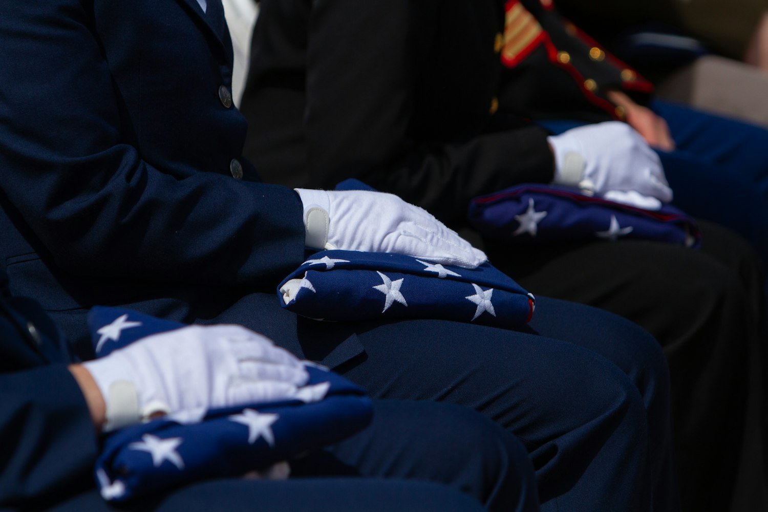 People in uniform carefully folding American flags at a ceremony