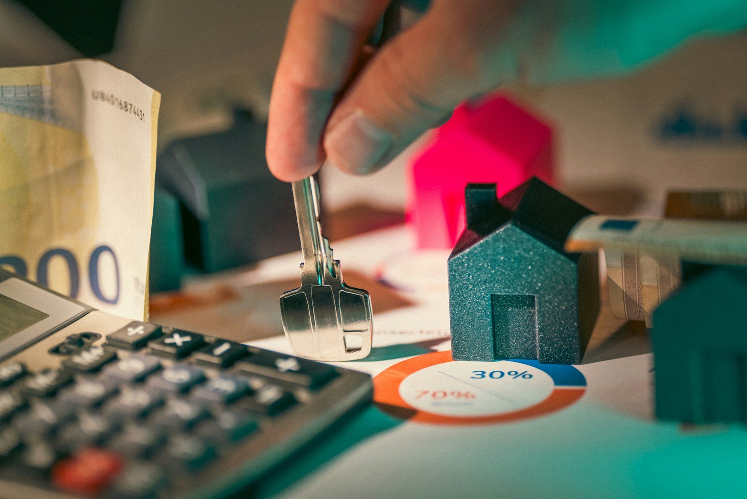 A hand holding a key over small house models, representing housing assistance vouchers