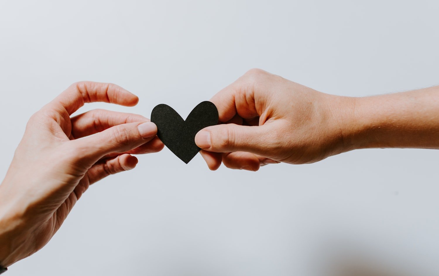 Two people holding a paper heart, representing shared sympathy and support