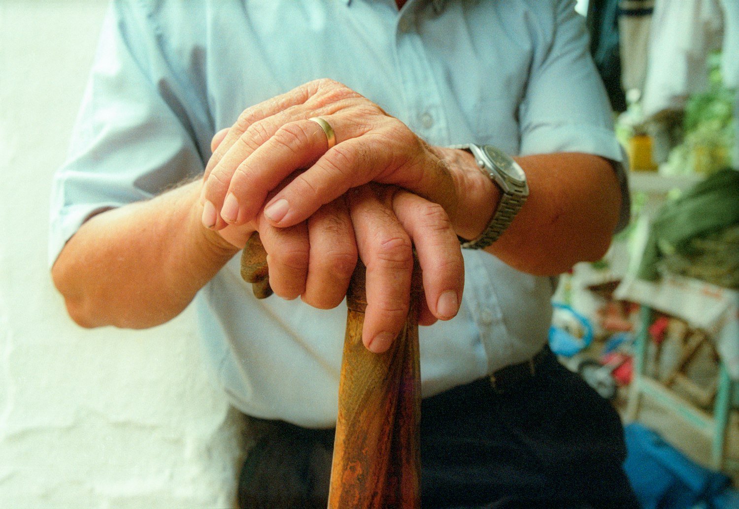 Weathered hands holding a walking stick, representing reduced mobility in later life