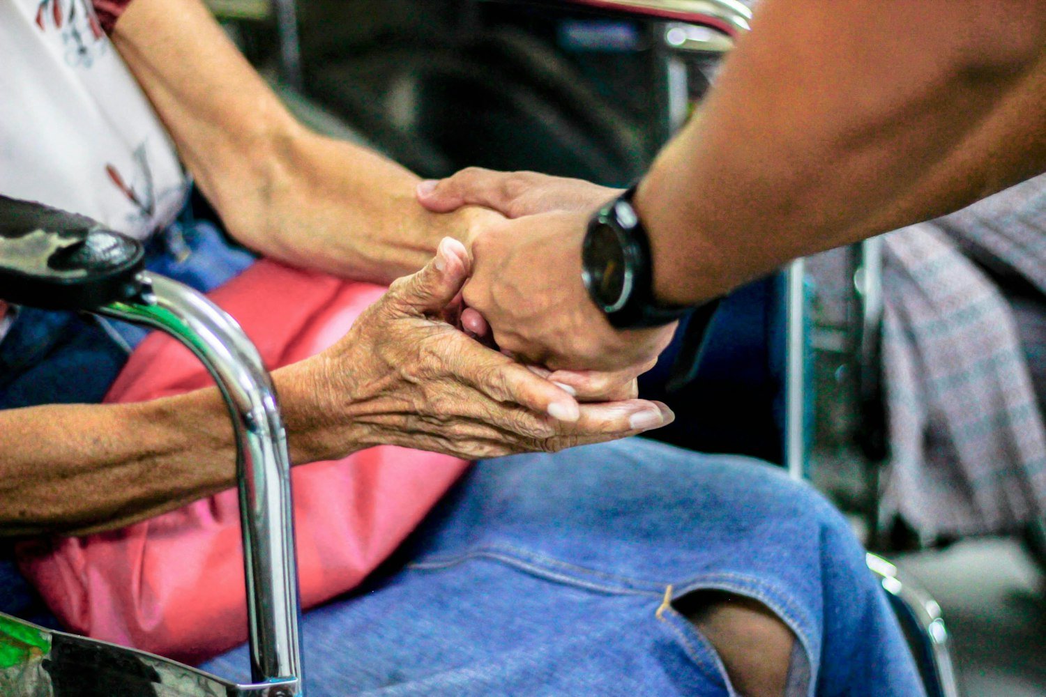 Two people holding hands while seated, representing support for a surviving family