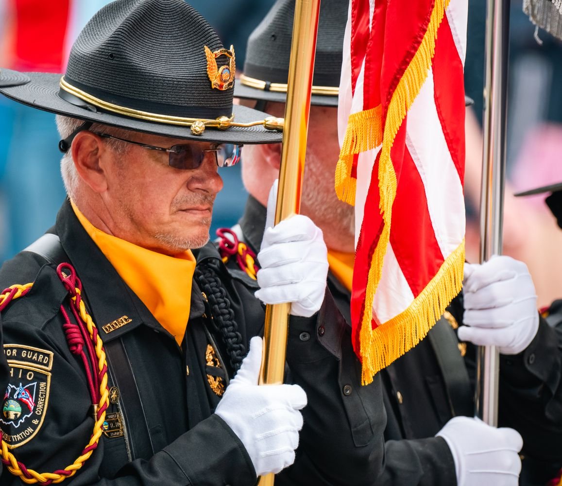 Honor Guard members in uniform holding an American flag during a formal ceremony