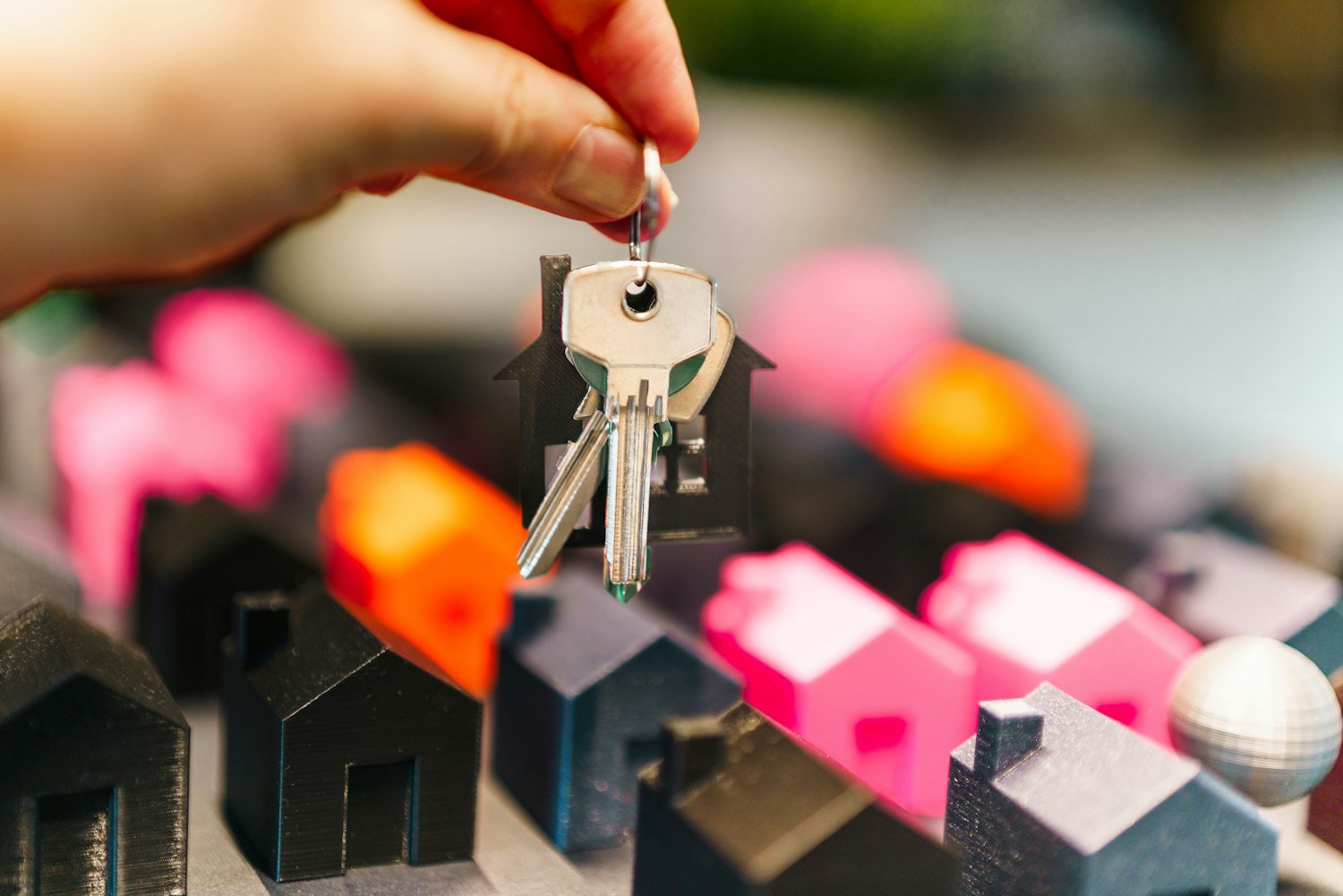 A hand holding house keys over miniature houses, representing Oregon's veteran home loan program