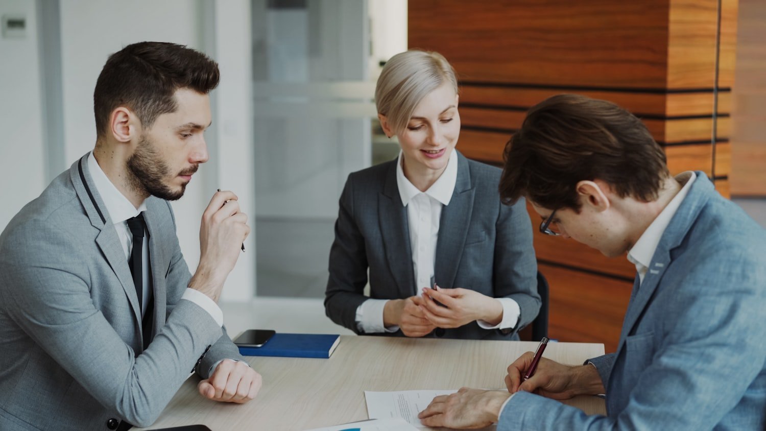 People reviewing and signing documents together at a table during a legal consultation