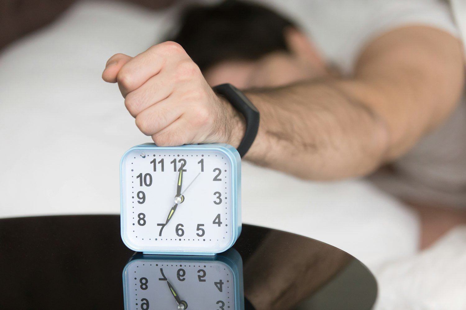 A person in bed with a clock, representing sleep monitoring and study data