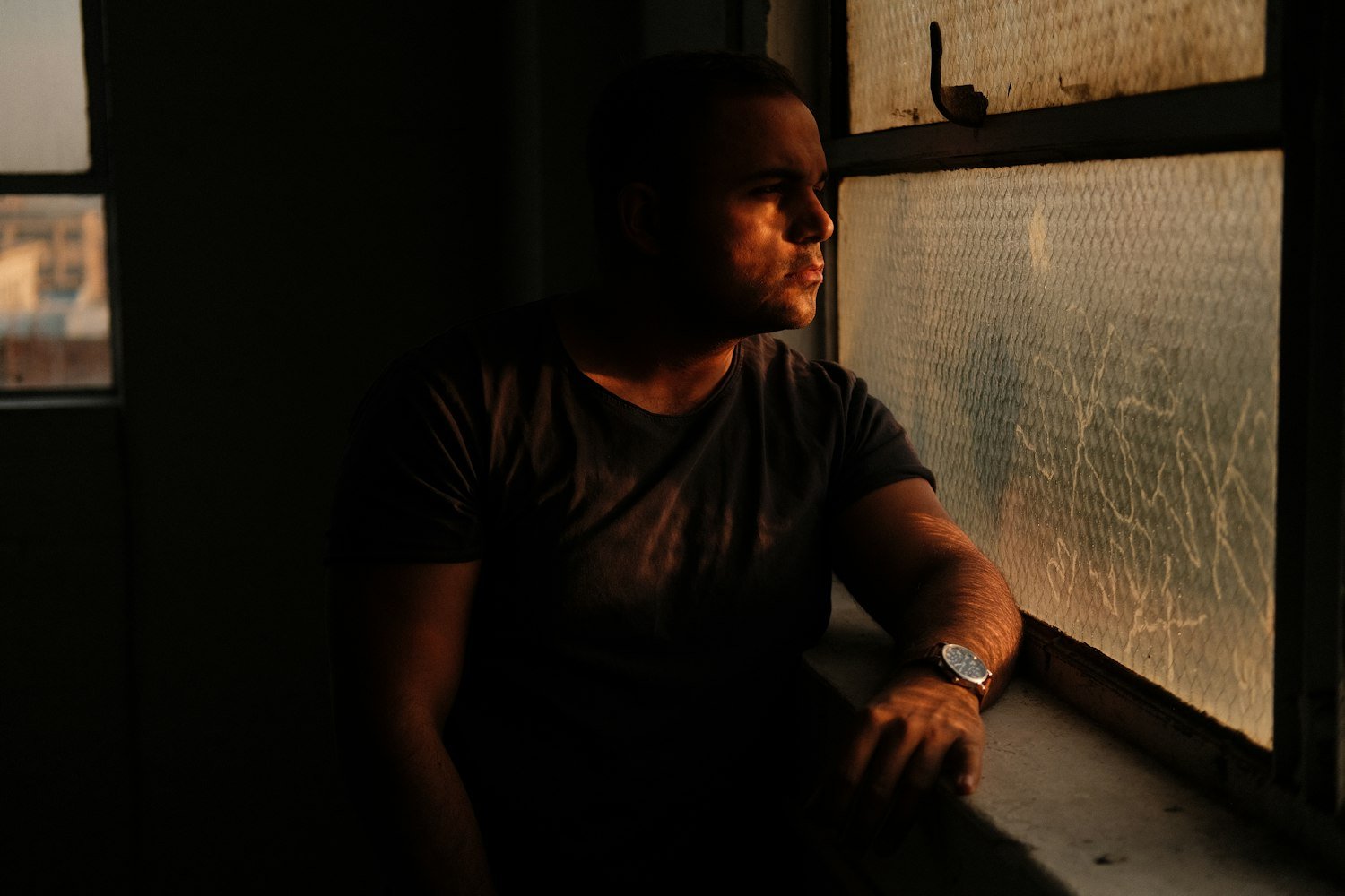 A person looking out a window at dusk, weighing whether to file for unemployability