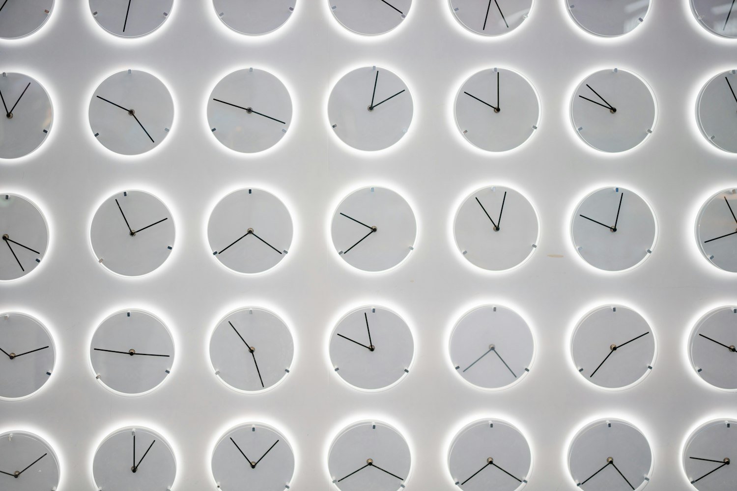 Many clocks on a wall, representing scheduling and appointment timing