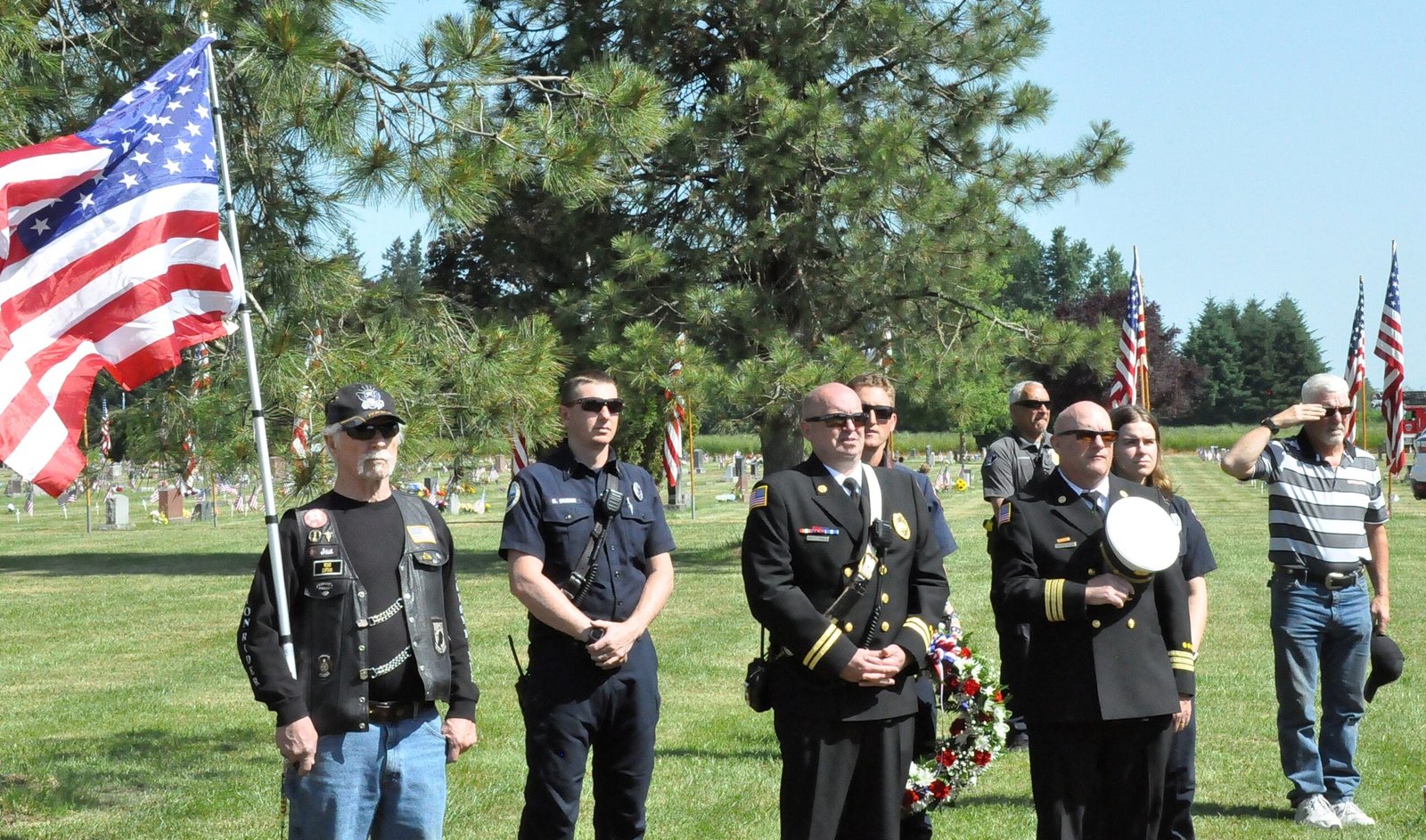 Post 51 members and community first responders at a Memorial Day ceremony, American flag flying