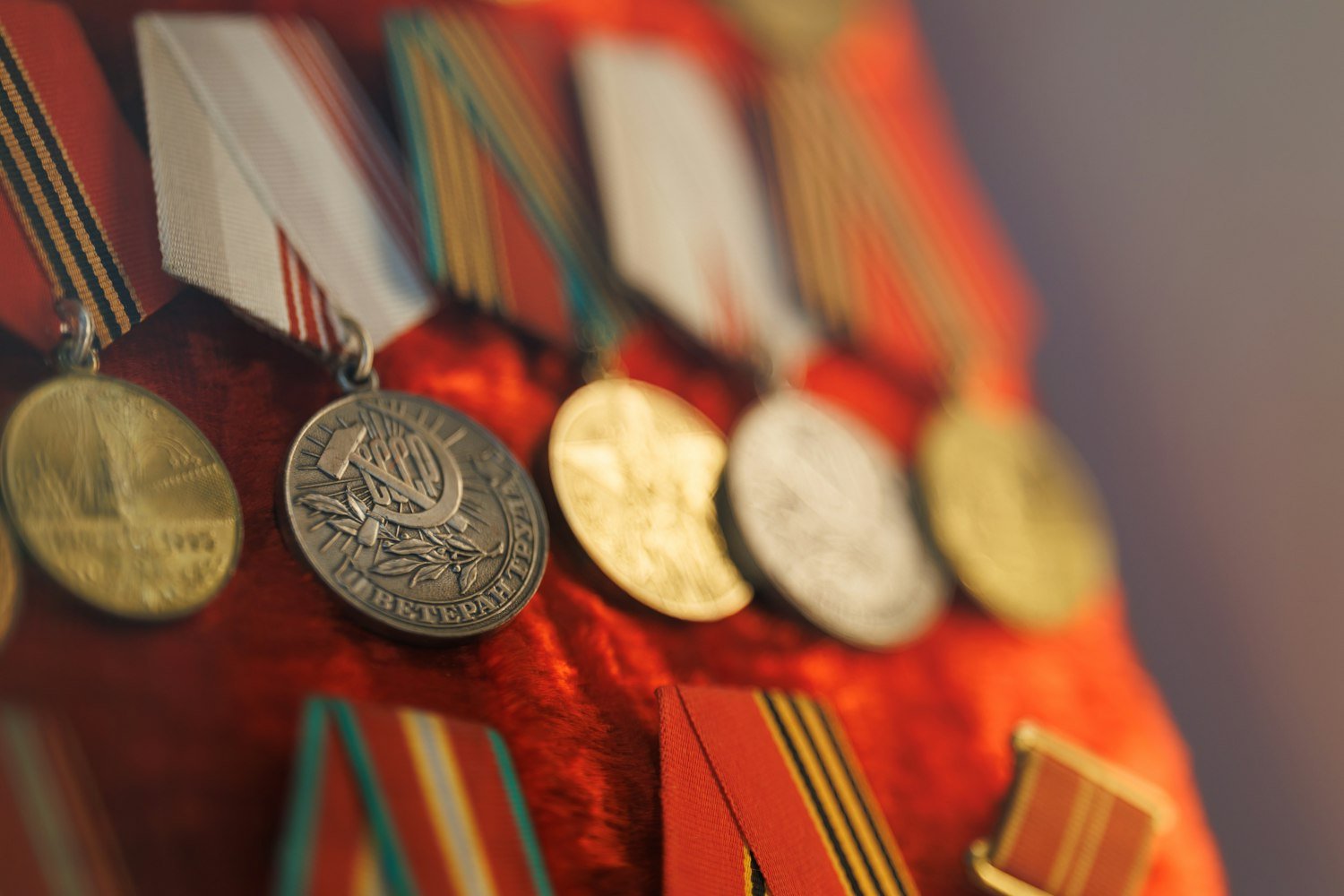 A row of vintage military medals with red ribbons, representing the combat-service medals required for VFW eligibility
