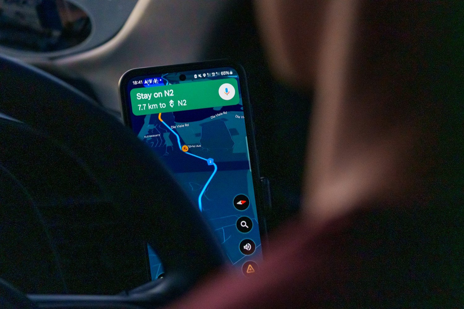 A navigation app on a smartphone in a car, as VA calculates average drive time by mapping software