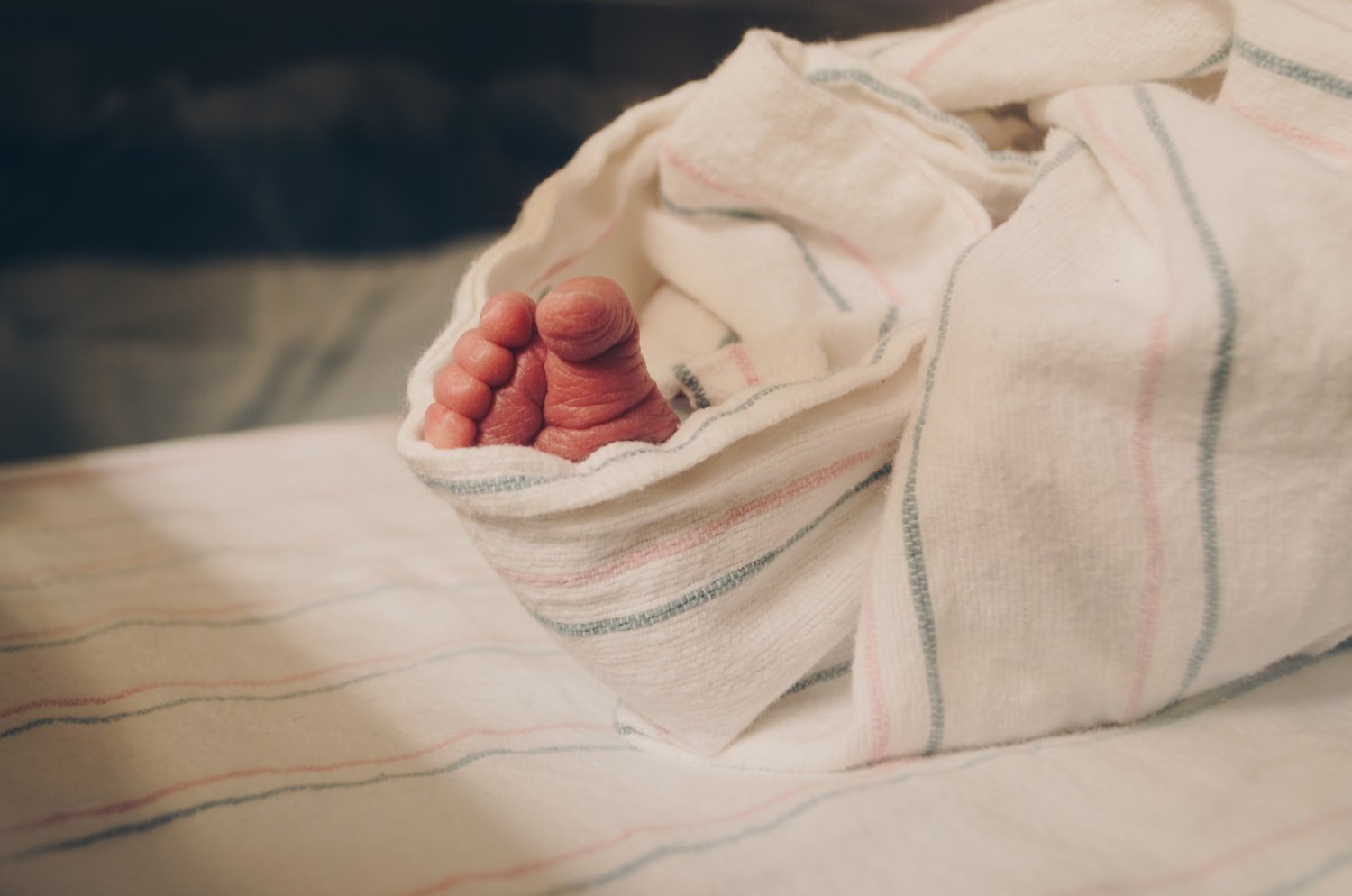 A newborn's hand under a blanket, the qualifying event that starts the one-year reporting window