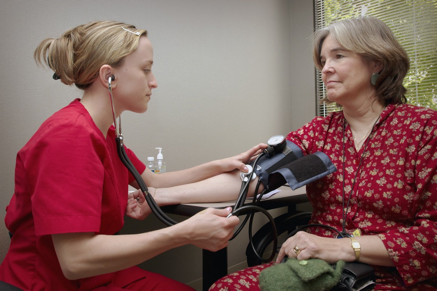 A nurse listening to a patient with a stethoscope during an exam