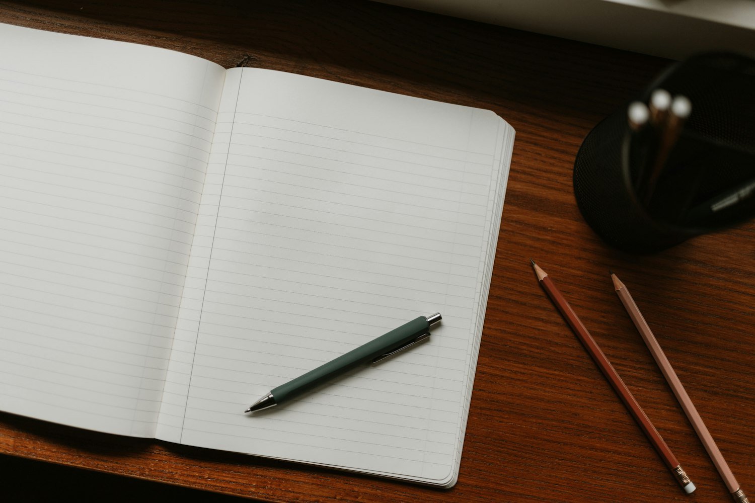 An open notebook and pen on a desk, for noting dates and details before writing
