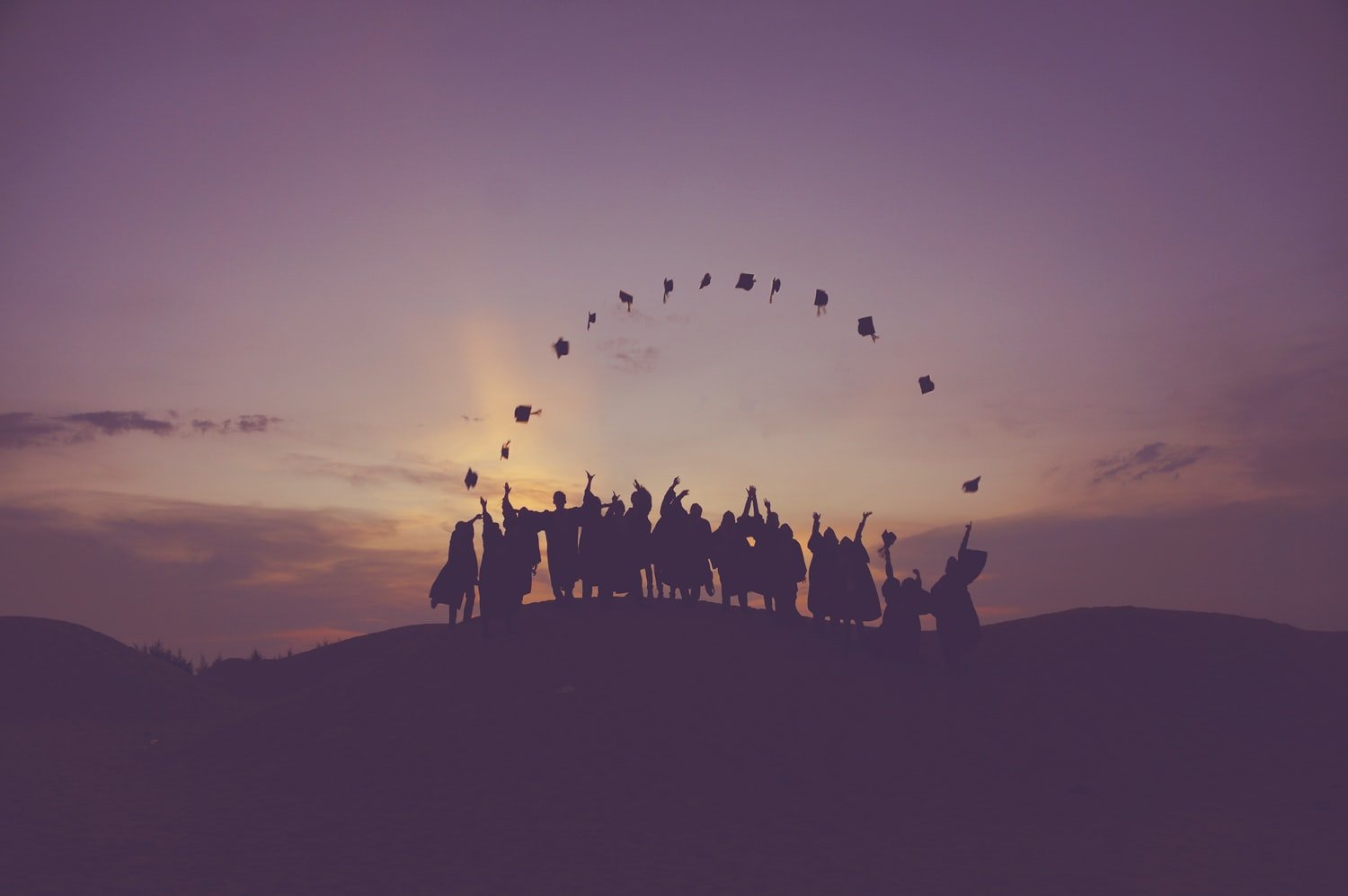 Silhouettes of people standing together on a hill, representing community and mutual support