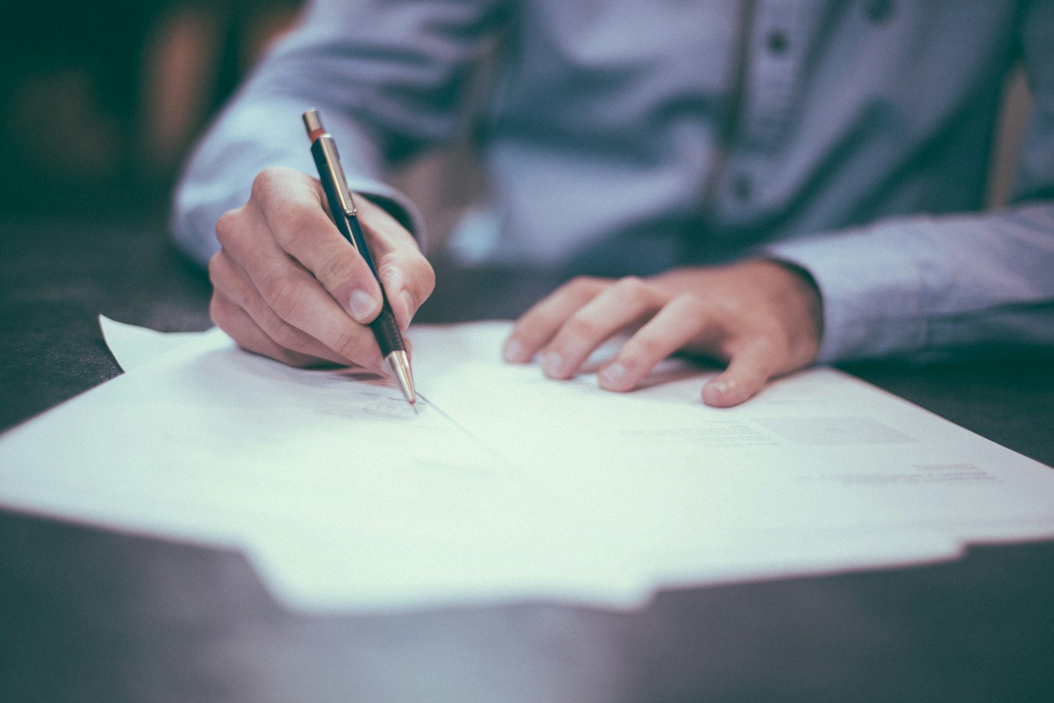 A person writing on paperwork, as when completing a discharge upgrade application