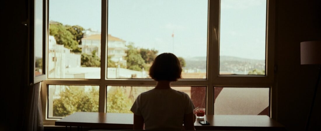 A person sitting at a table looking out a window in a quiet moment