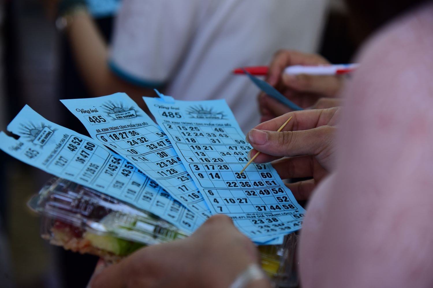 Players holding bingo cards and daubers during a community bingo night