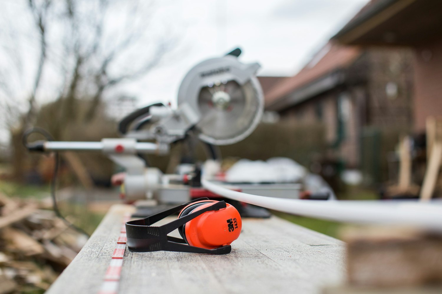 Protective earmuffs beside a power saw, the hearing protection often unavailable in service