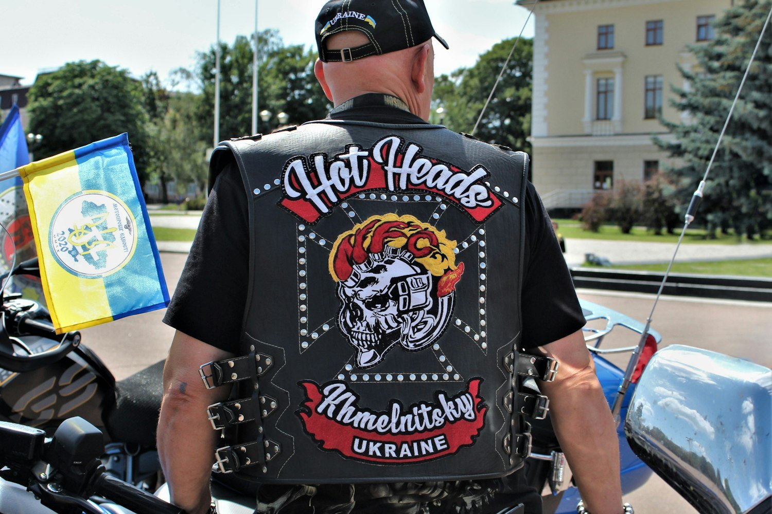 A rider in a leather vest standing next to a motorcycle