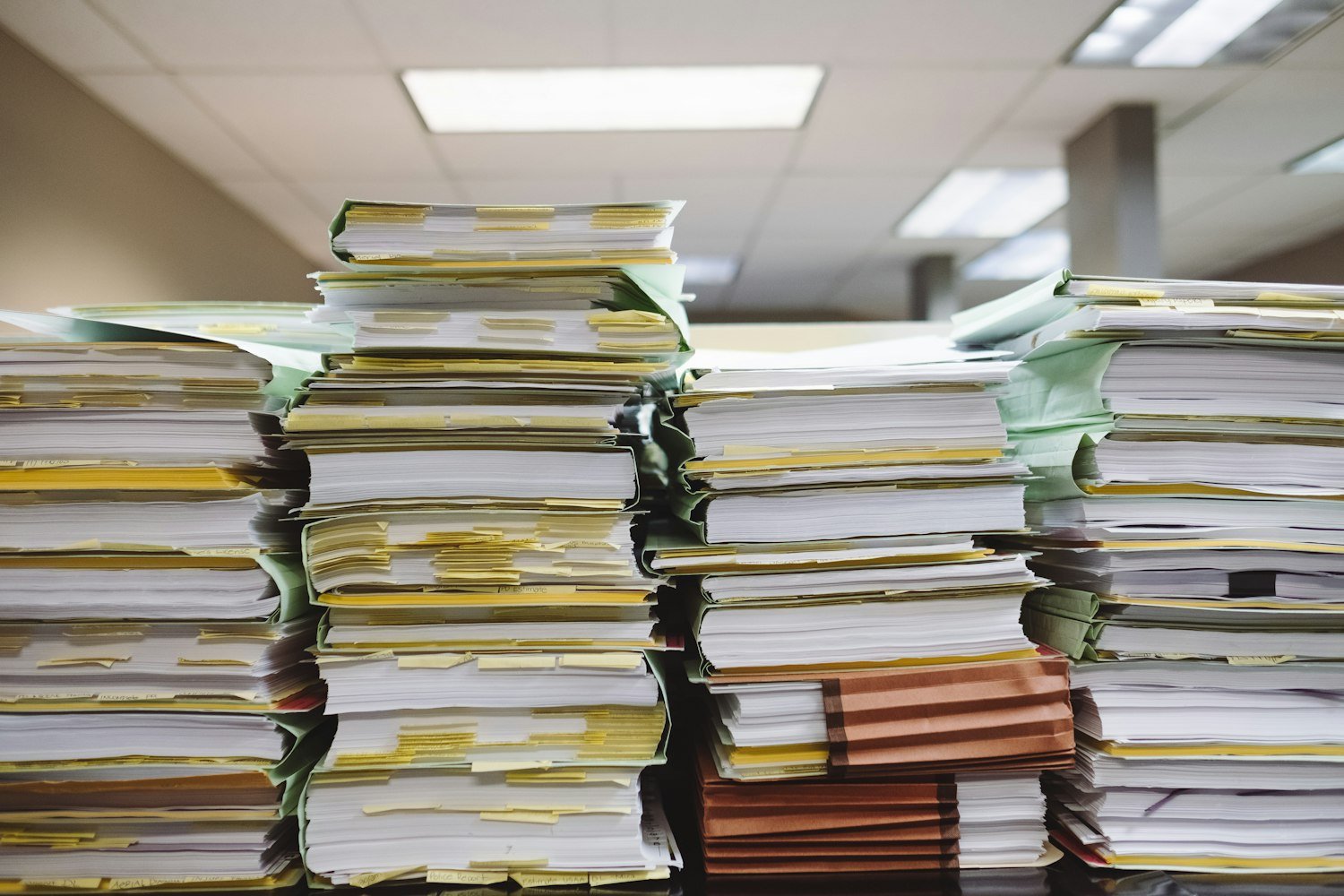 Stacks of paper documents and file folders, representing the service and medical records needed for a VA claim
