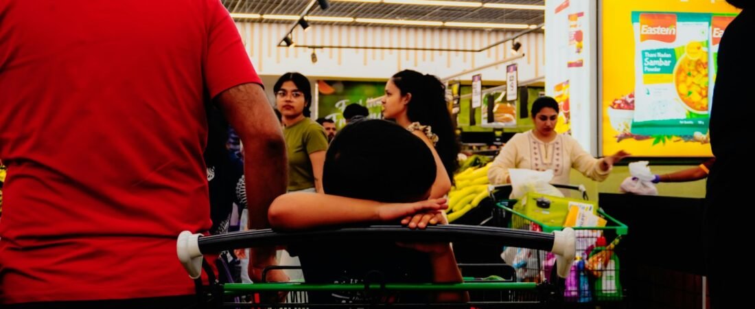 People shopping in a brightly lit supermarket aisle, like a military commissary