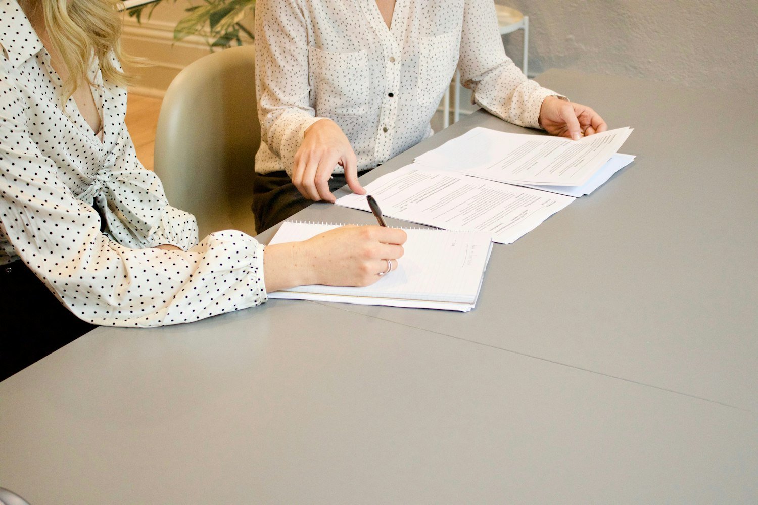 One person helping another review and sign documents at a desk