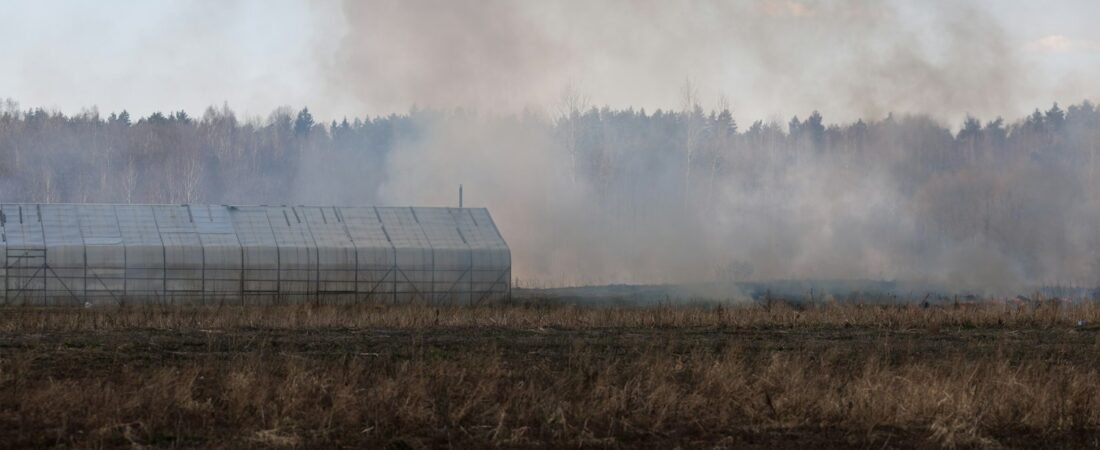 Smoke rising over a dry field, representing the open-air burn pits many service members were exposed to