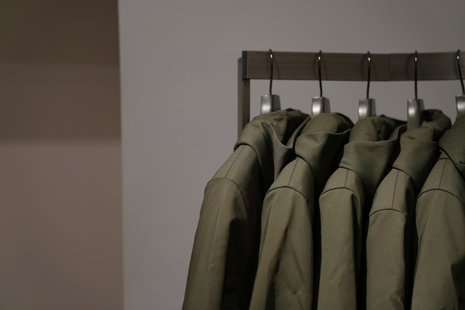A row of uniforms hanging on a rail, representing military service left behind