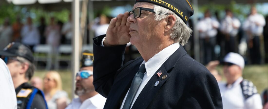 A veteran in uniform saluting during an outdoor ceremony