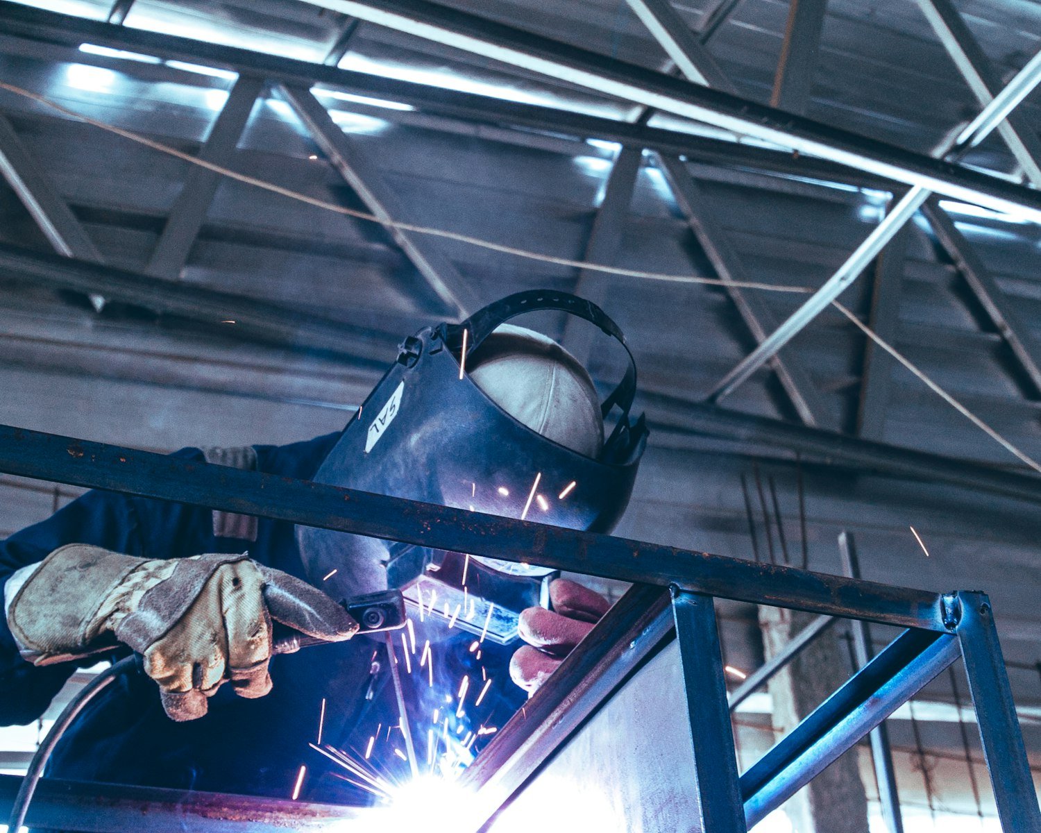 A welder working on metal, since survivor benefits also cover trade and apprenticeship programs