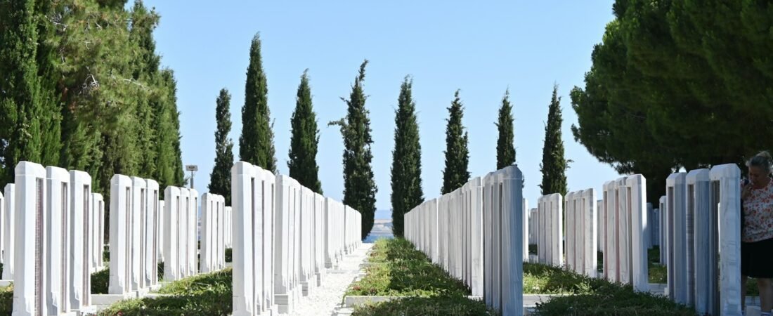 Rows of white military headstones on a green lawn at a veterans cemetery