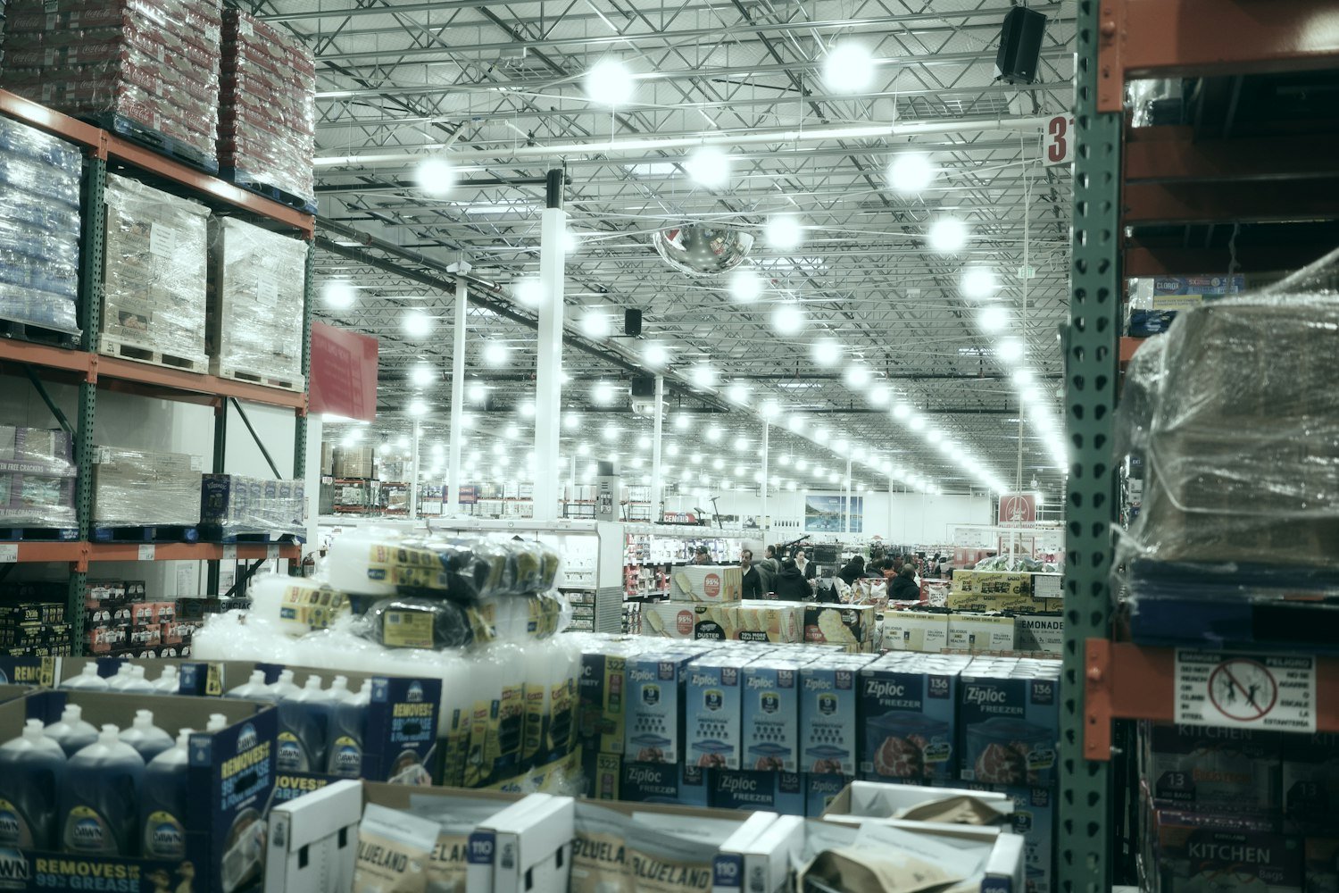A wide, brightly lit warehouse store aisle stocked with goods