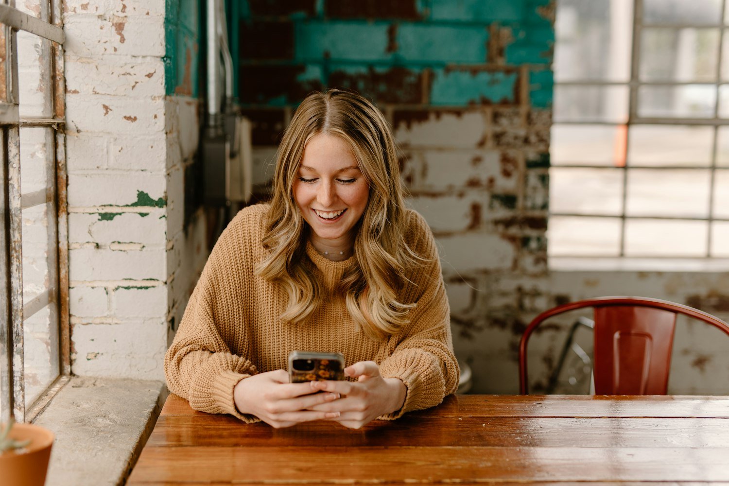 A woman checking her phone at a table, as when calling to schedule a VA appointment